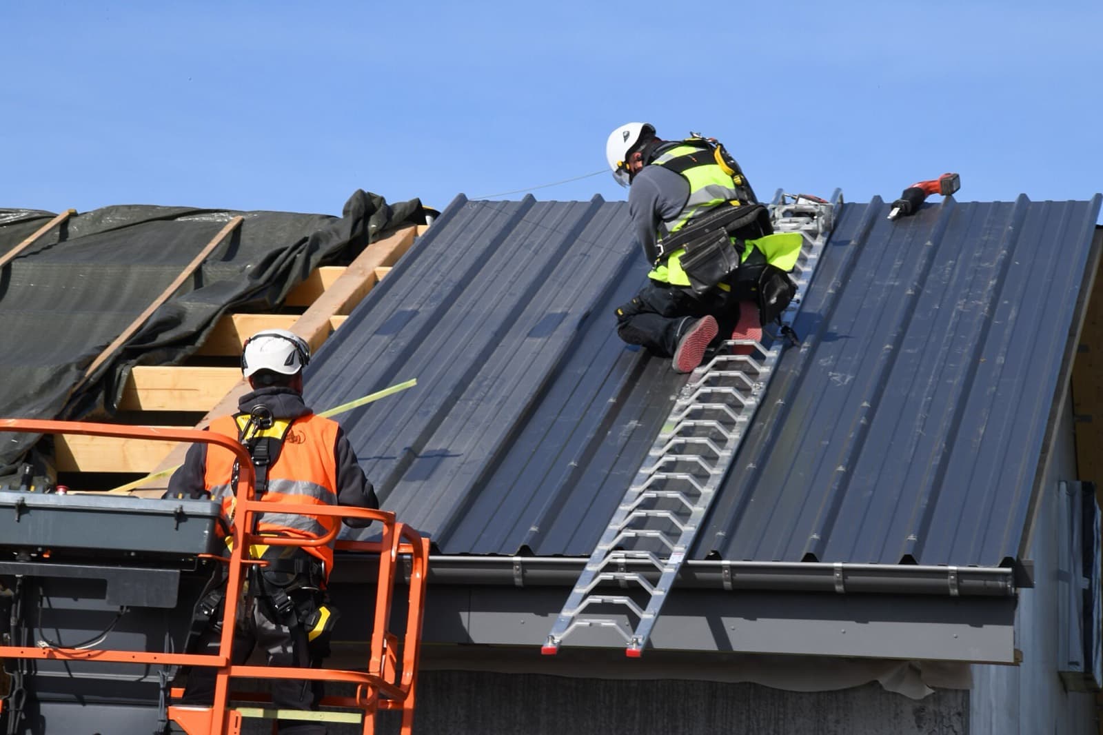 Workers in harnesses fitting a new panel roof