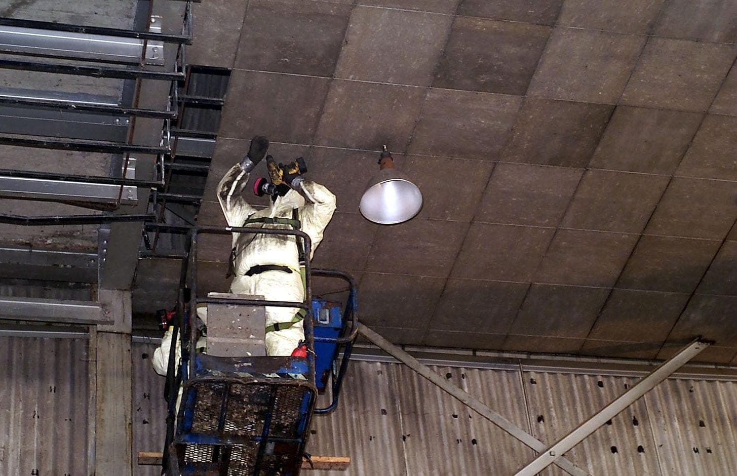 Worker in a protective suit with breathing equipment removing material