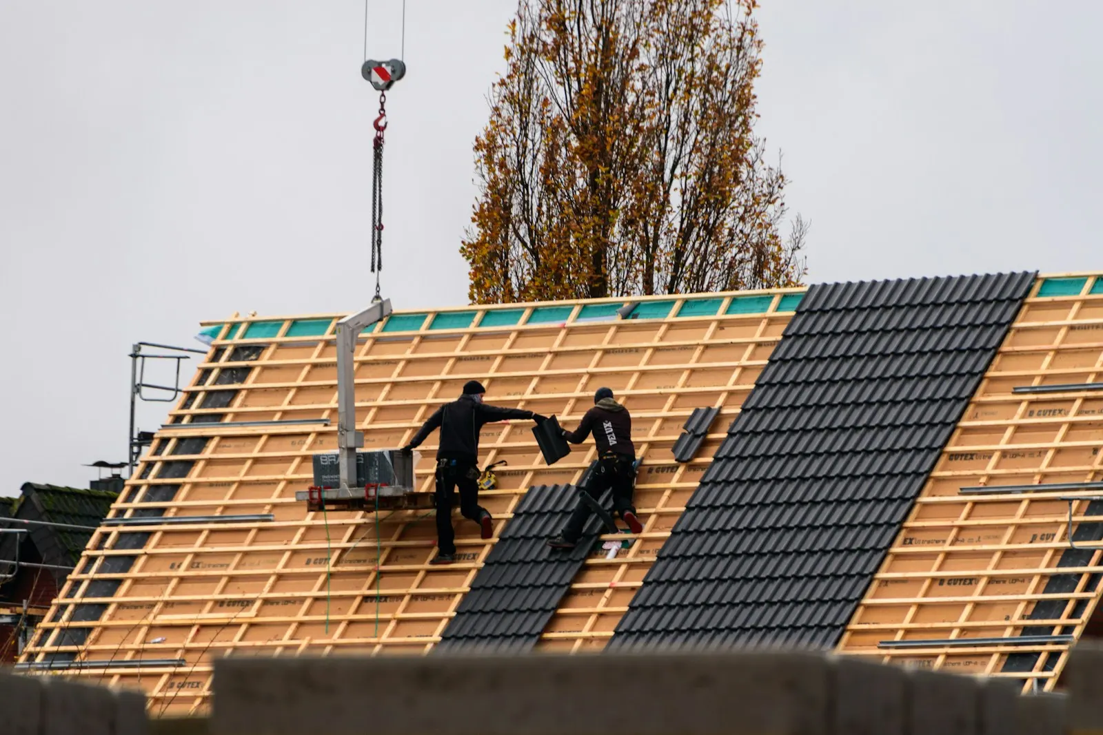 Workers laying the new roof covering on the battens