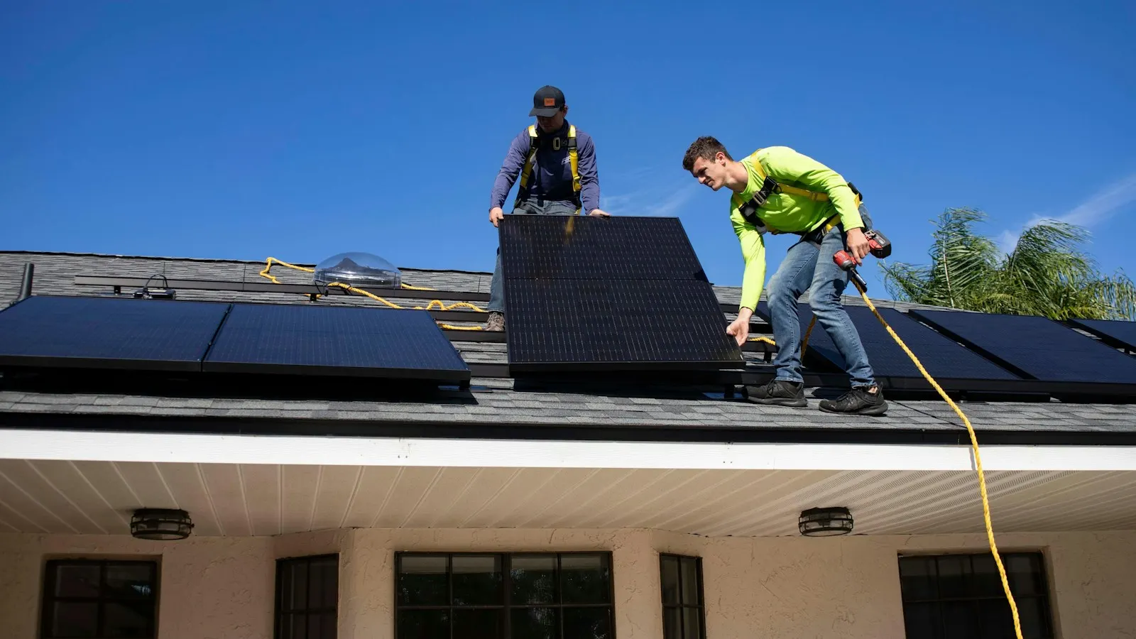 Two workers fitting solar panels on a roof