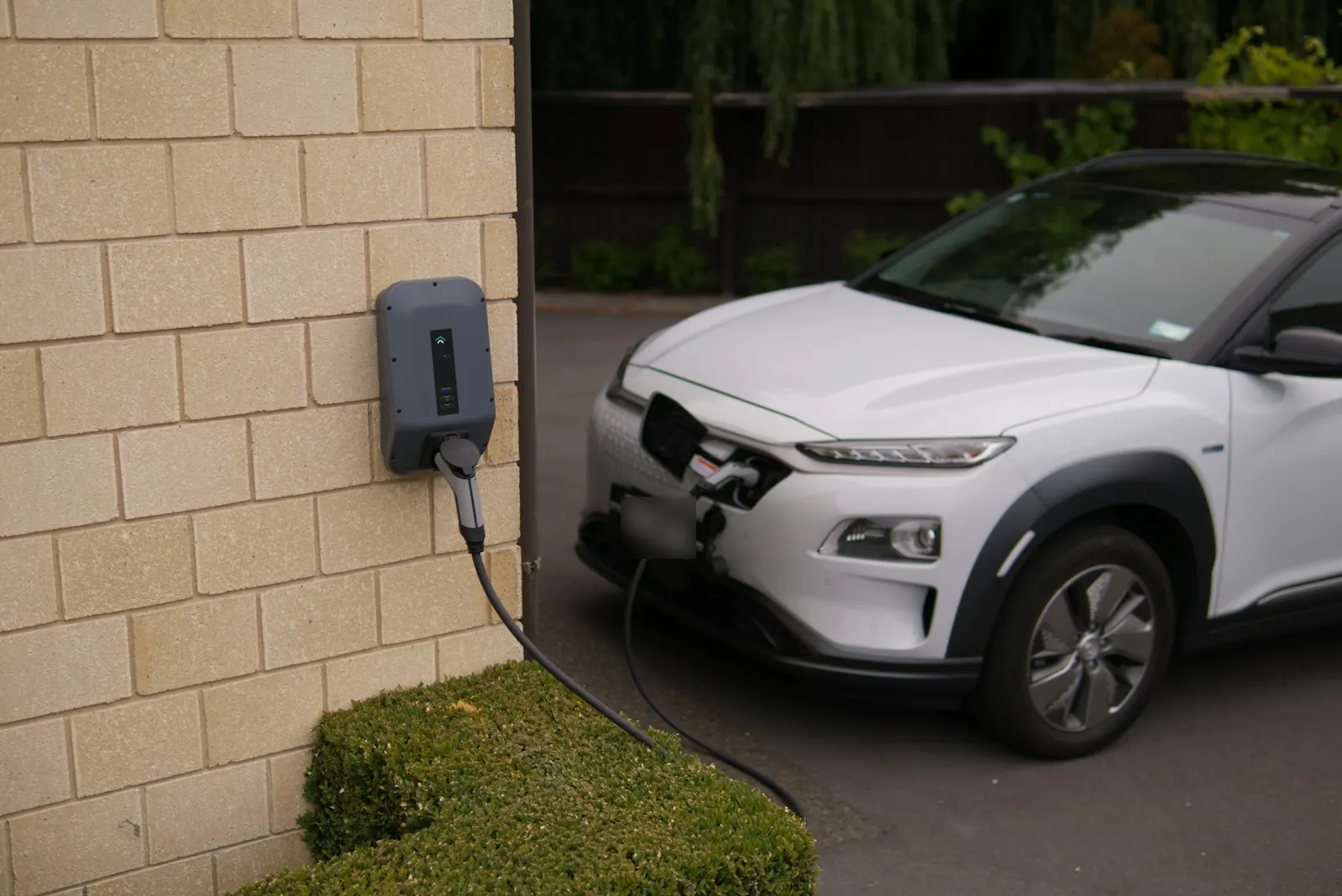 Electric car charging next to a house wall