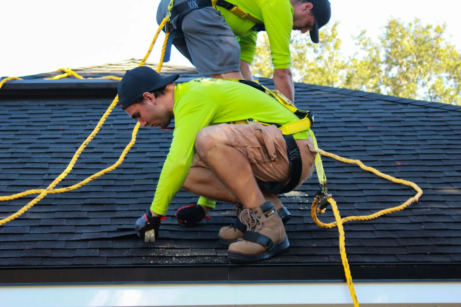 Workers with harnesses and safety ropes working on a roof